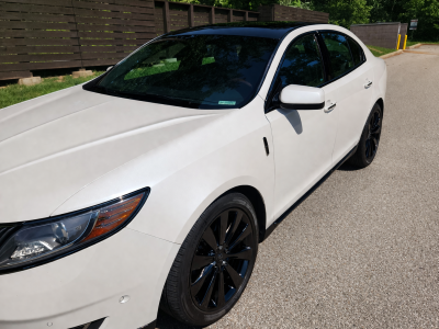 Luxury sedan under sunny sky.png